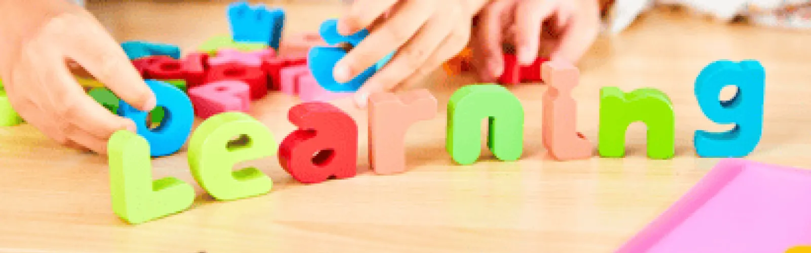 children's hands playing with colorful wooden letter blocks