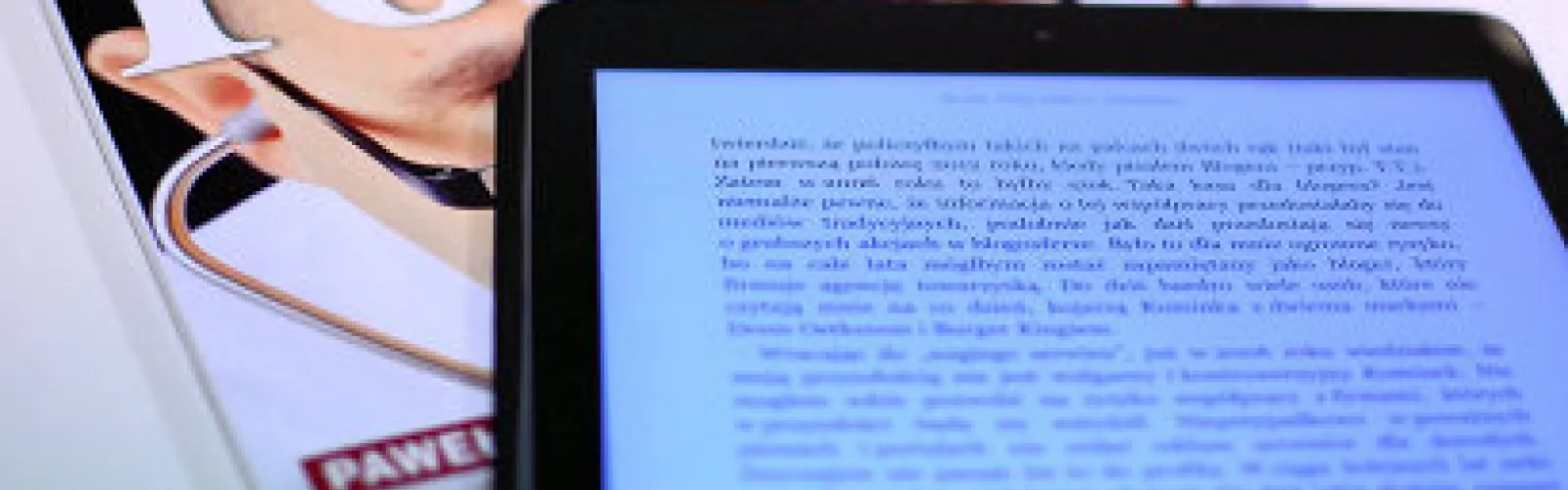 An ereader screen with a partial view of a magazine sitting beneath it